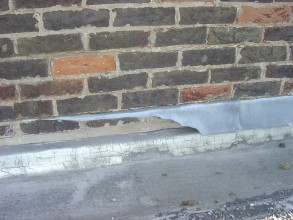 Severely deteriorated flashing at a parapet wall